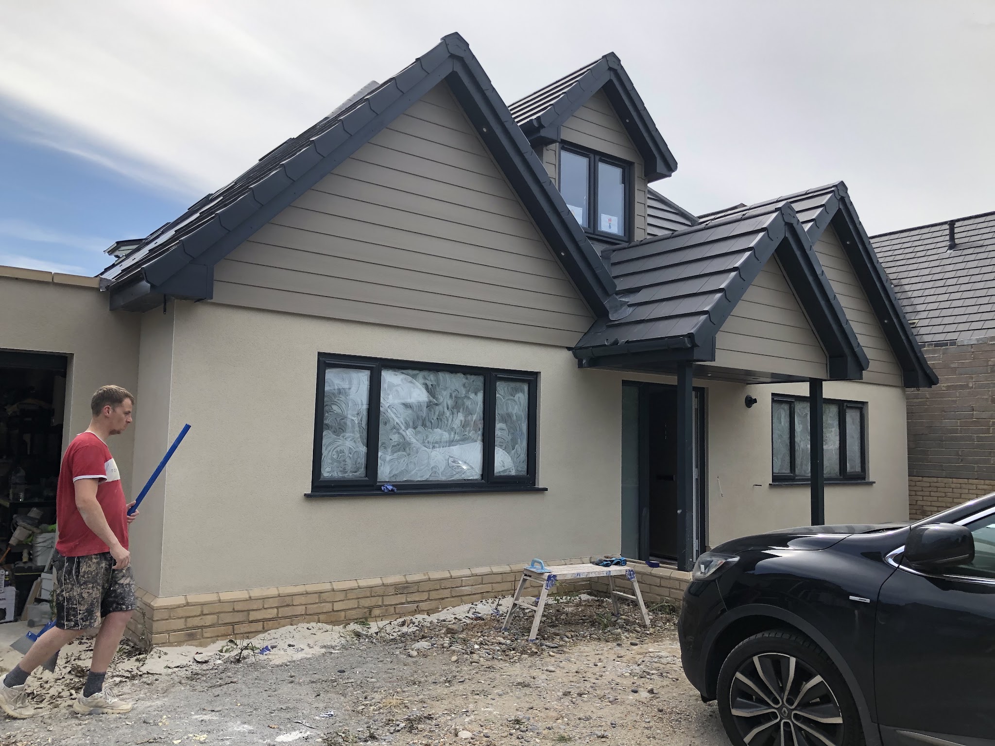 On site at a chalet bungalow with fresh cream render and grey cladding
