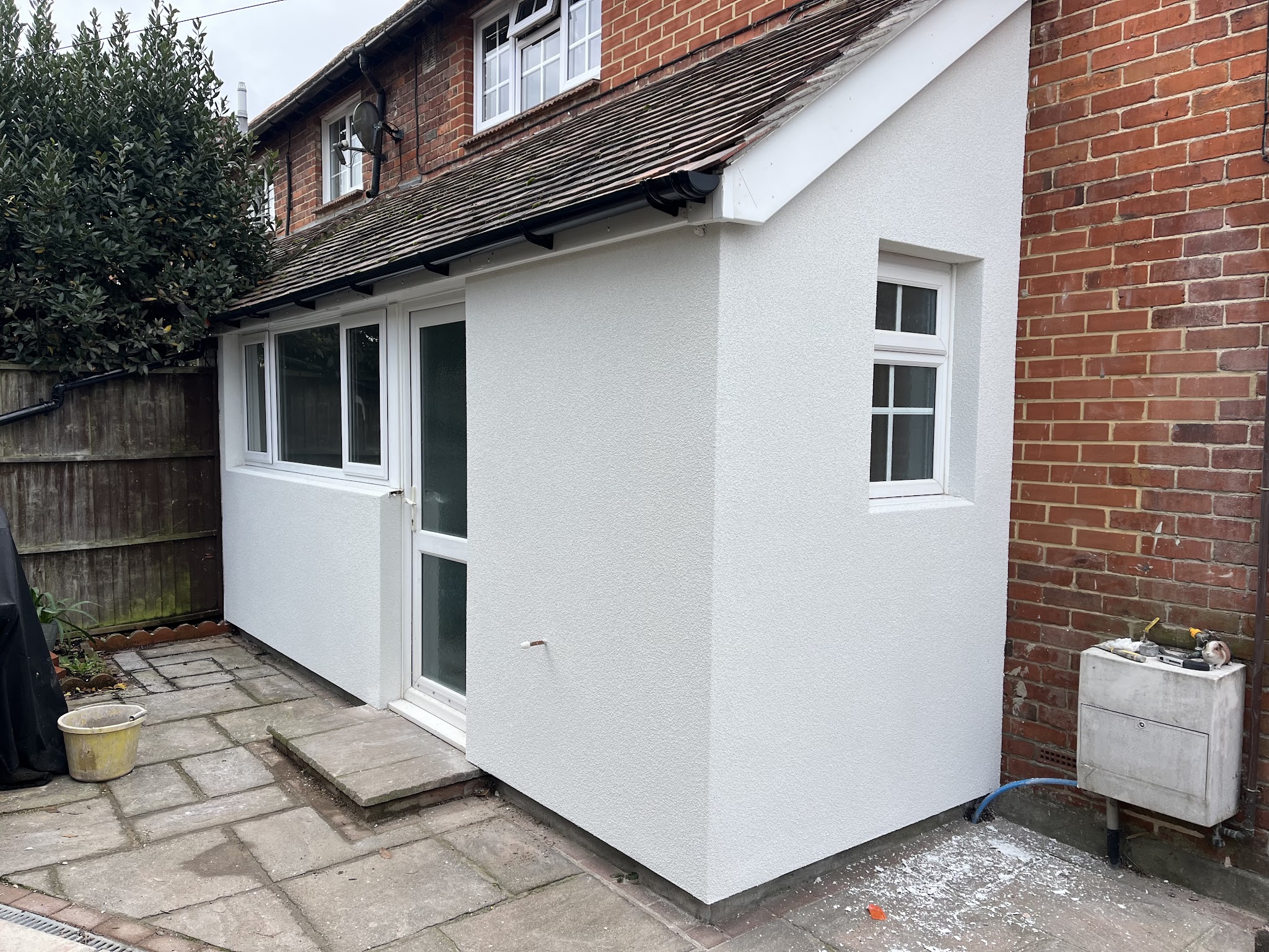 White rendered side extension next to a brick chimney