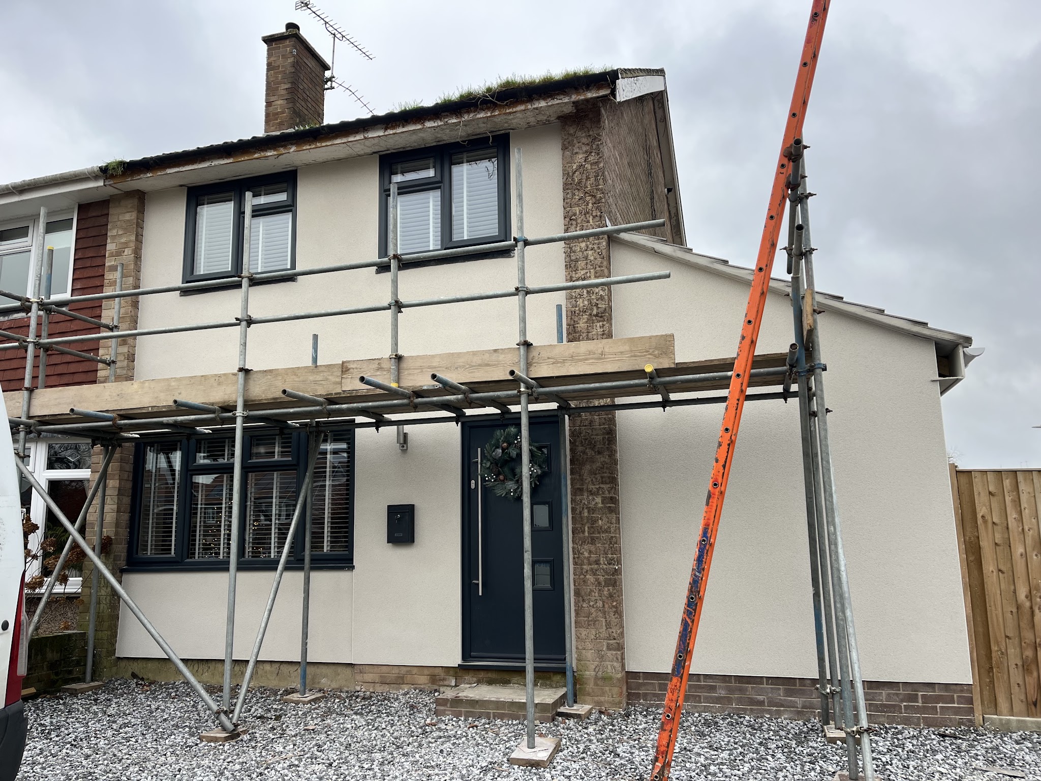 Semi-detached house under scaffolding with fresh cream render