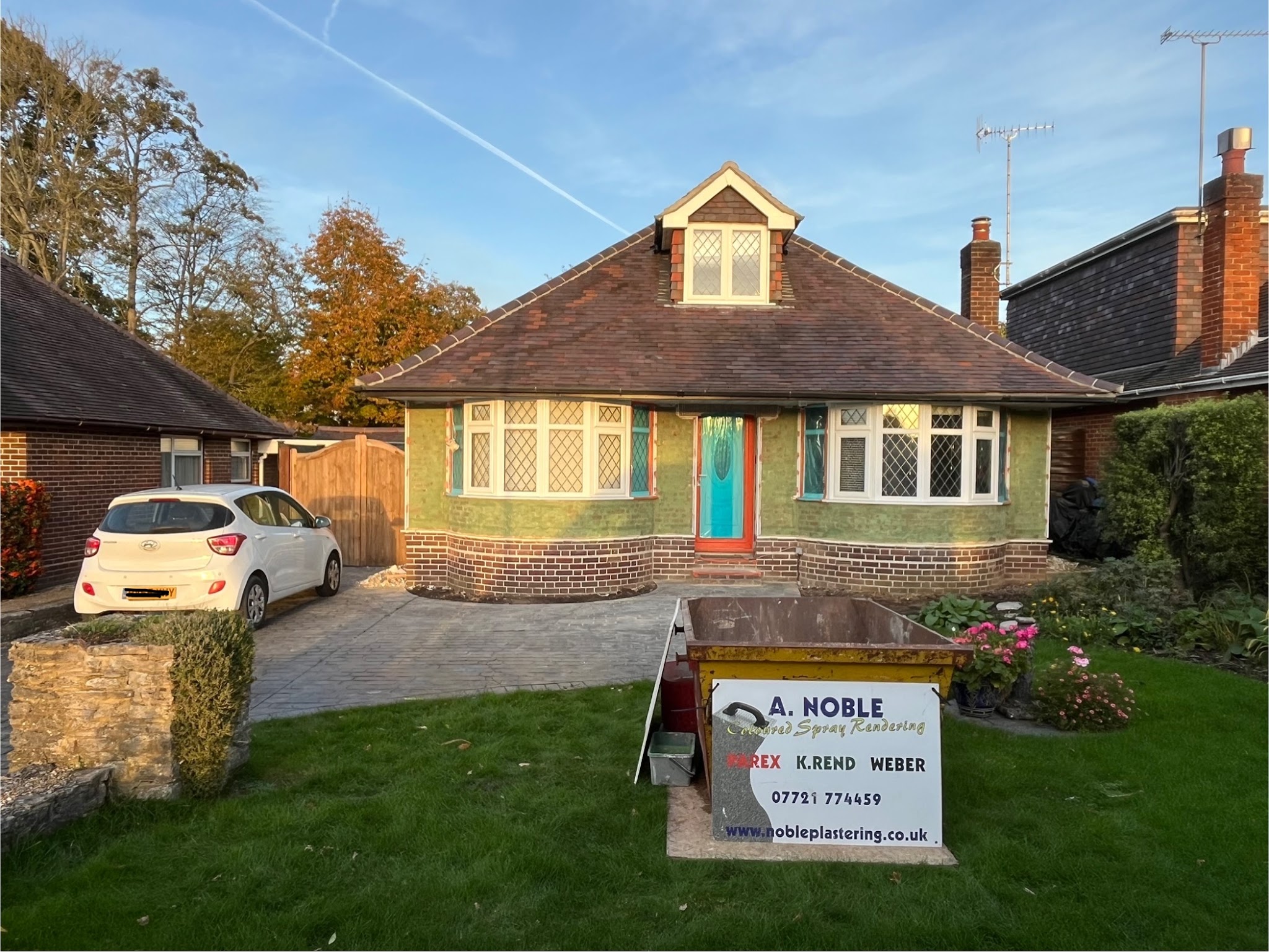 Our A. Noble Coloured Spray Rendering board on the lawn of a bungalow